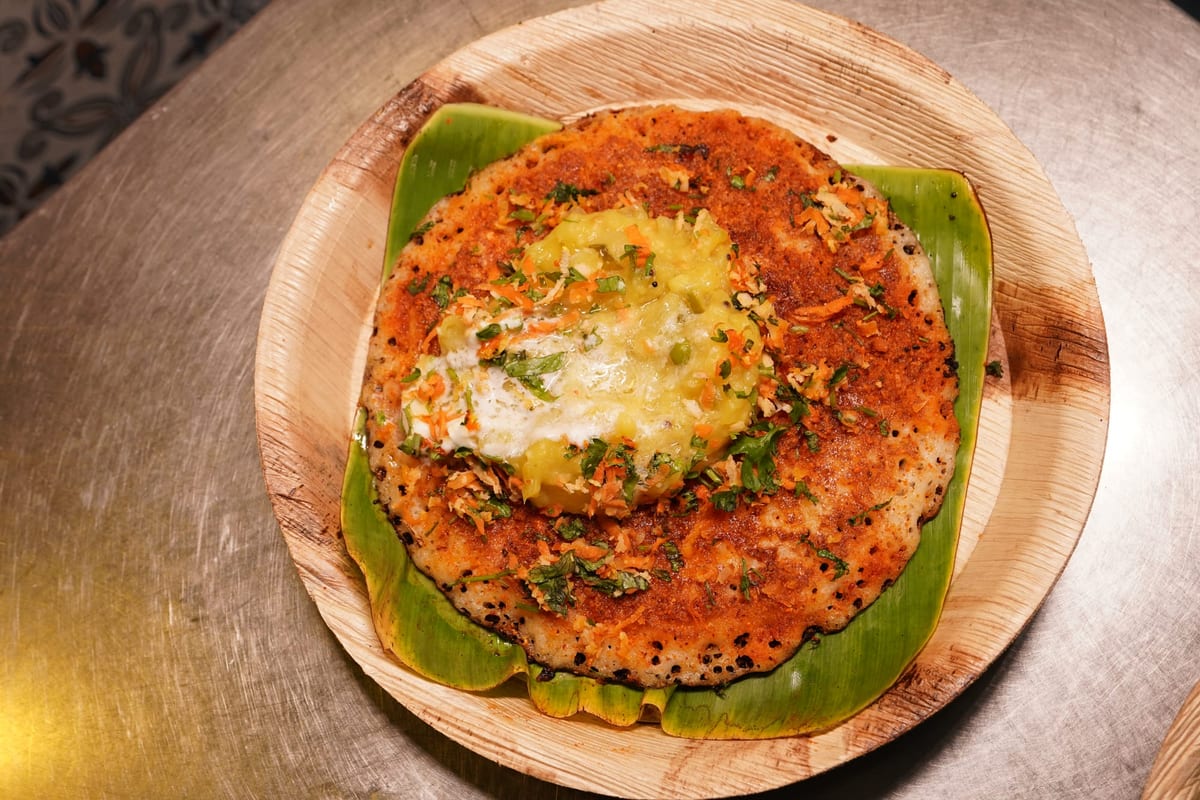 Open benne masala dosa hand-spread on a cast-iron tawa